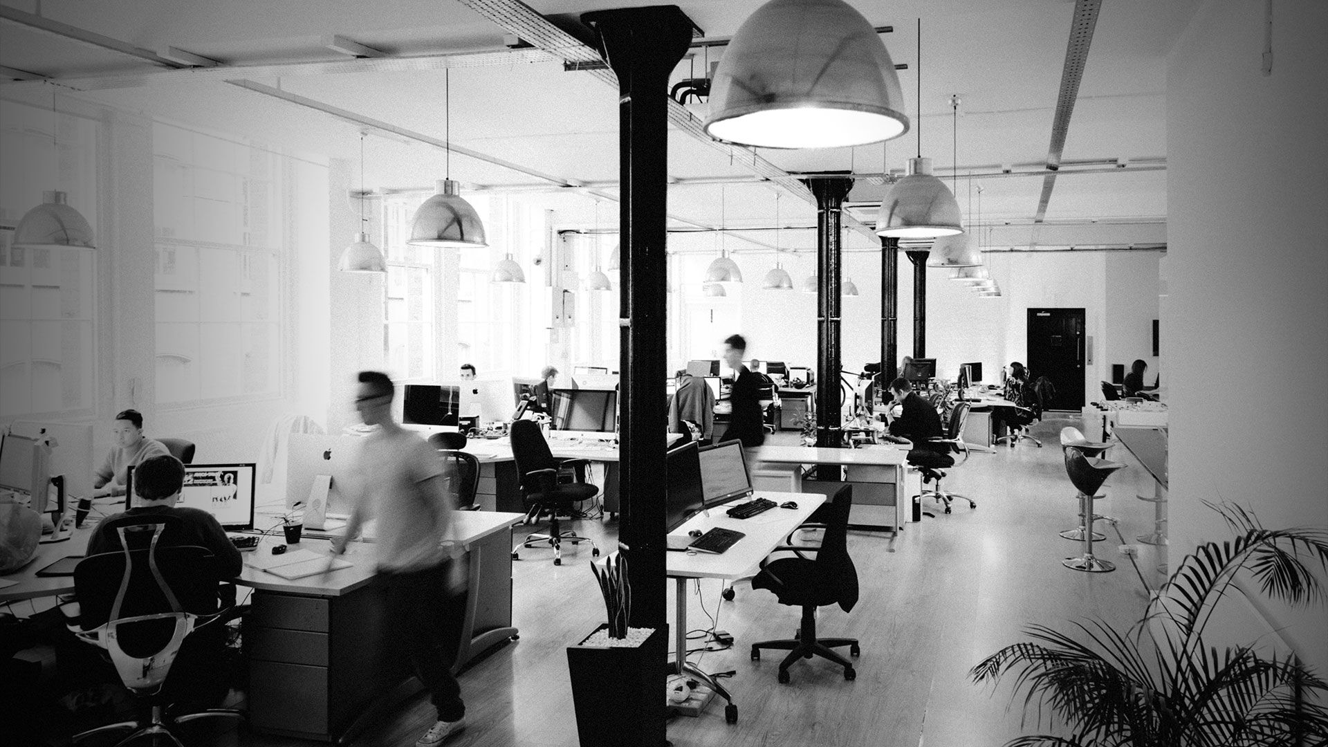 The Codegent studio in London: long desks under industrial pendant lights, one person walking through in a blur